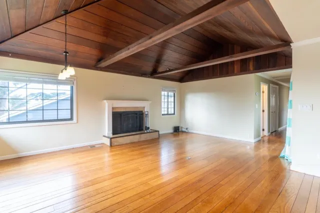 an empty room with wooden floor a ceiling fan and windows