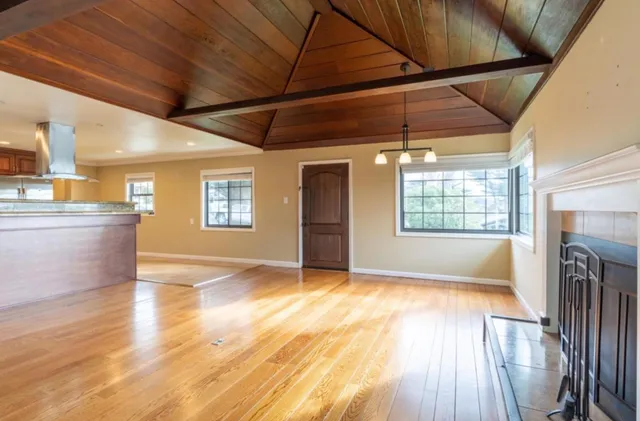 a view of an empty room with window and wooden floor