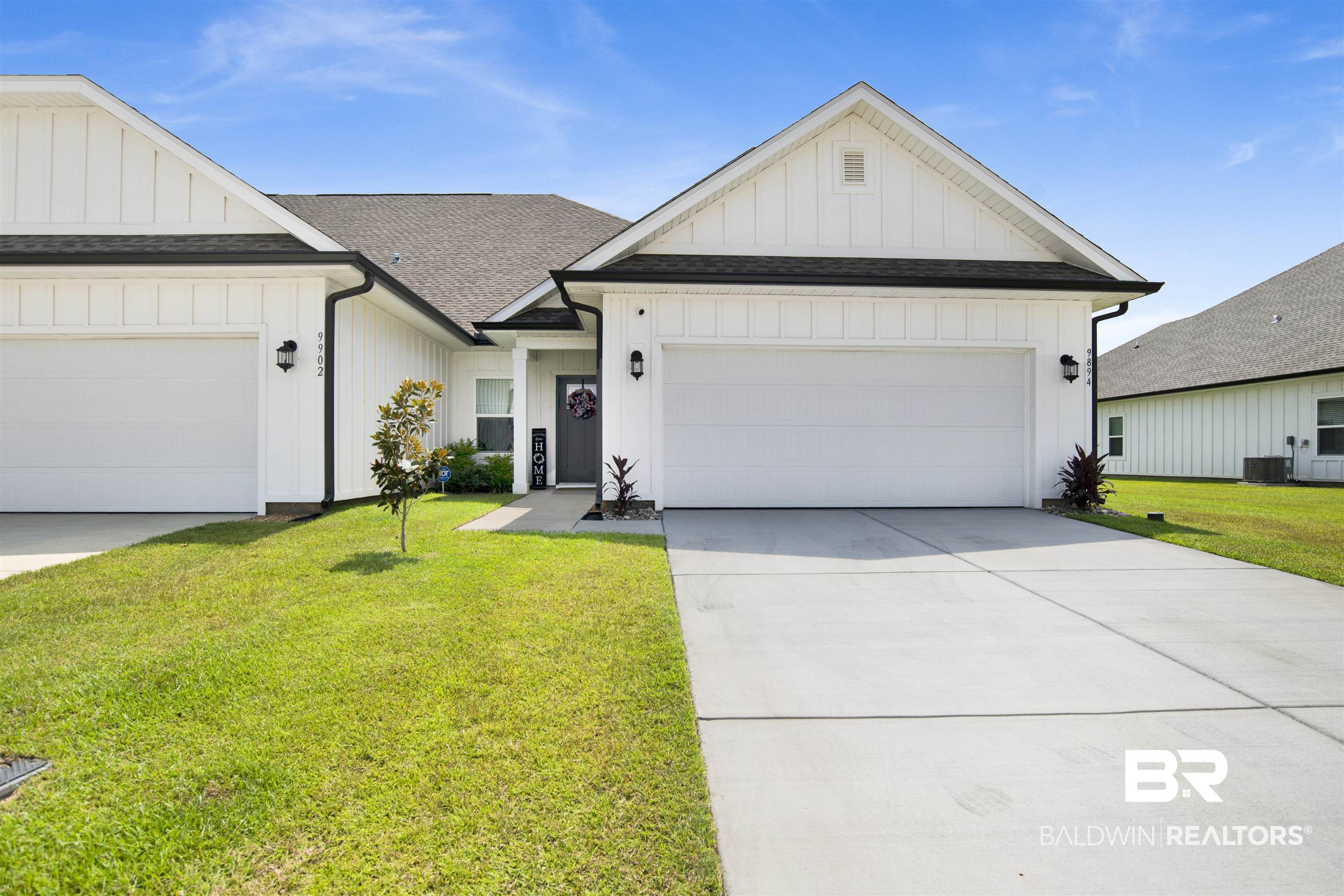 Modern farmhouse featuring board and batten siding, a shingled roof, an attached garage, and a front yard