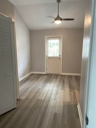 an empty room with wooden floor cabinet and windows