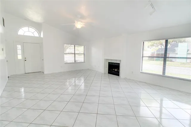 an empty room with windows and fireplace