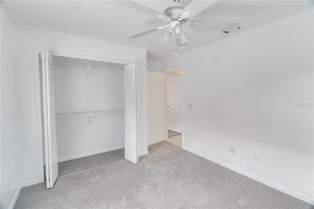 an empty room with a ceiling fan and a window
