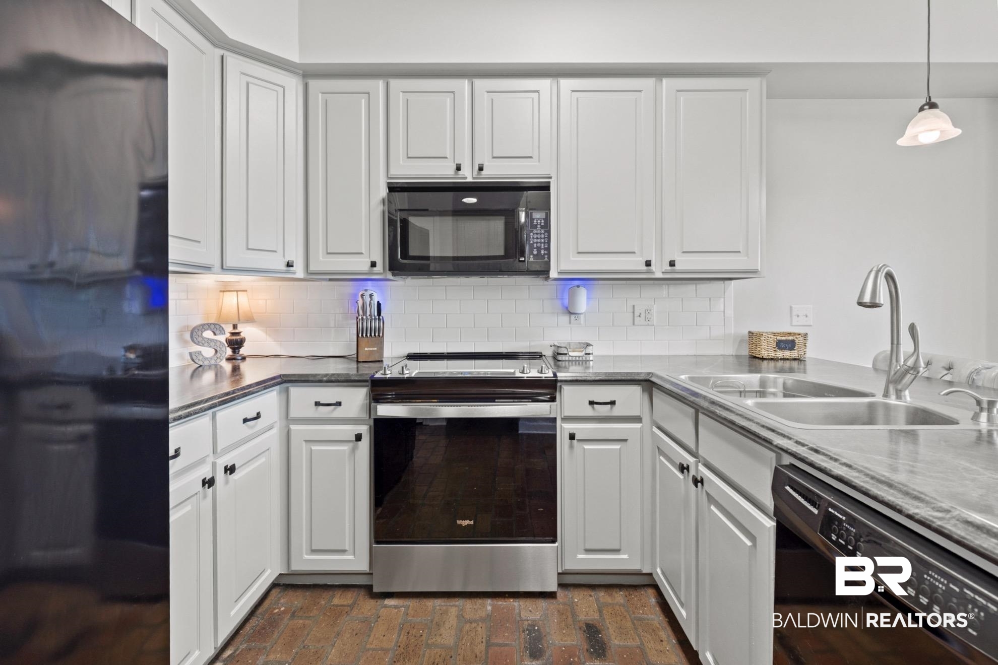 12171 Marguerite Drive Coden, AL 36523 - Photo 9 of 44 White shaker-style cabinetry with dark hardware, stone-finish countertops, subway tile backsplash, and stainless steel appliances