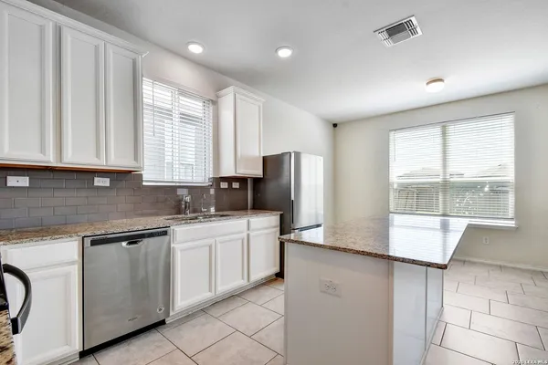 a kitchen with stainless steel appliances granite countertop a refrigerator a sink a stove and white cabinets
