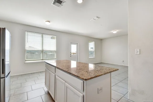 a kitchen with granite countertop a sink and white cabinets