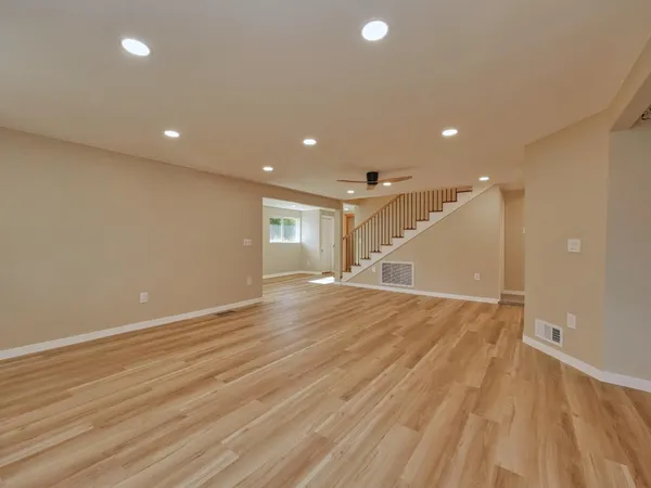 a view of empty room with wooden floor and fan