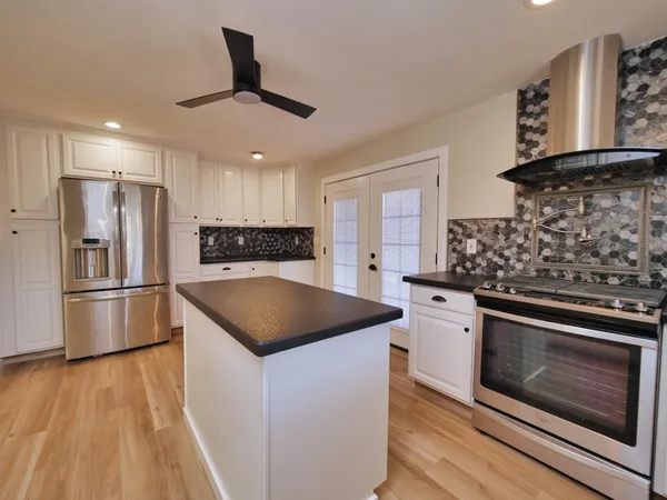 a kitchen with stainless steel appliances granite countertop a stove a sink and a refrigerator