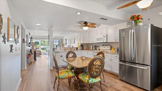 a kitchen with stainless steel appliances a table chairs and a refrigerator