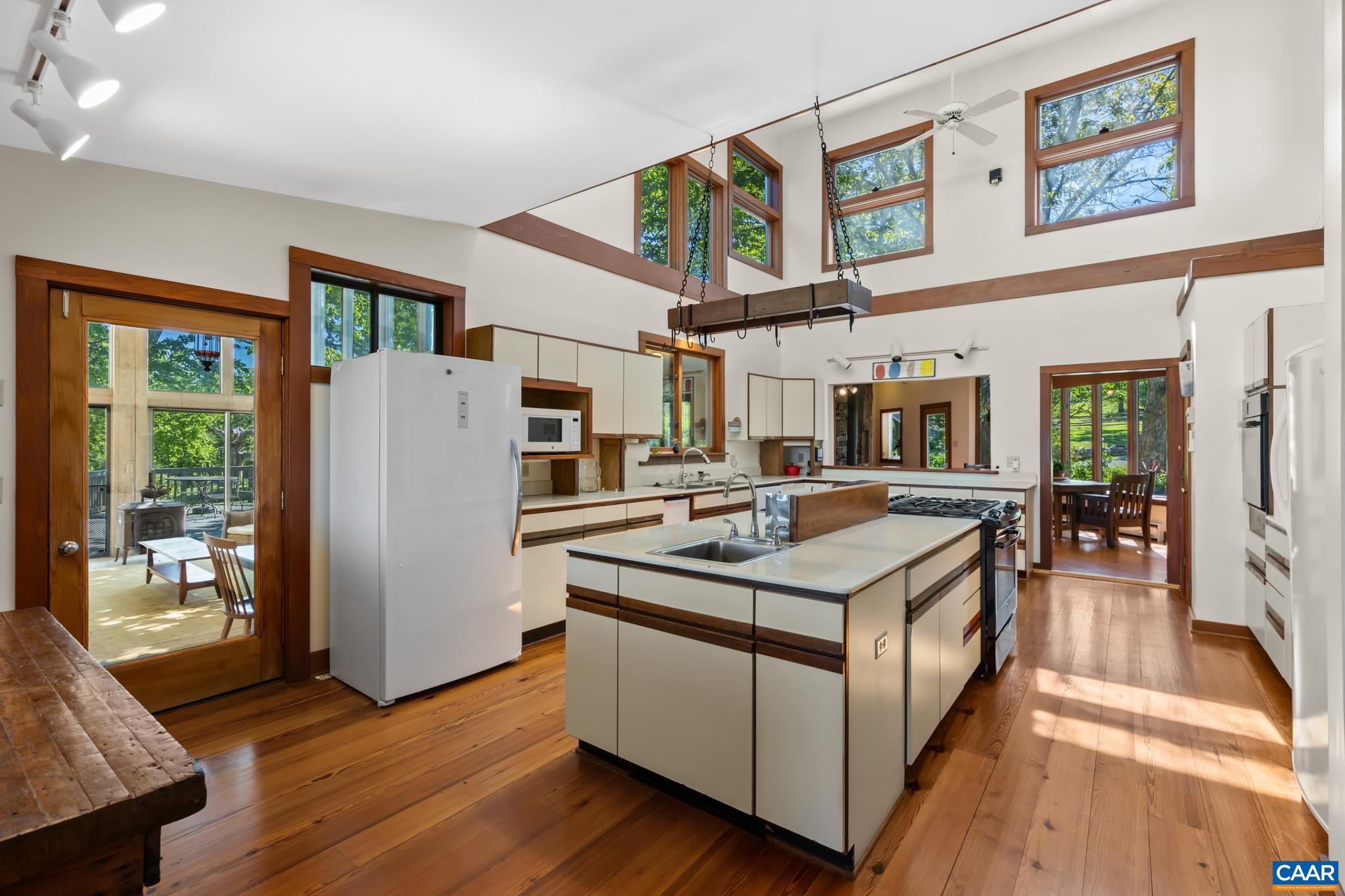7098 Bucks Elbow Mountain Road Crozet, VA 22932 - Photo 18 of 57 a kitchen with stainless steel appliances granite countertop a stove top oven a refrigerator a dining table and chairs with wooden floor