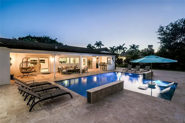 a view of a swimming pool with lawn chairs under an umbrella