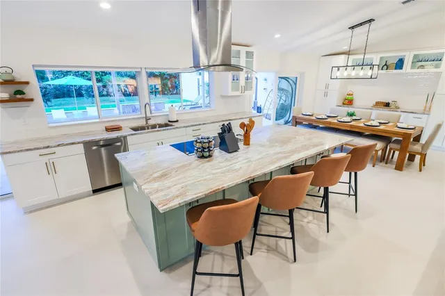 a close view of a dining table chairs and kitchen view with a large window