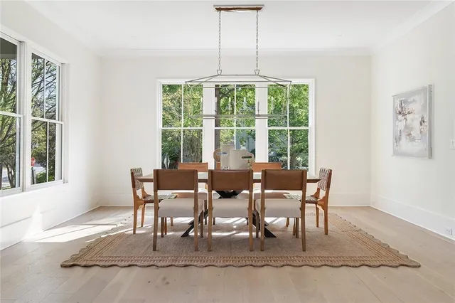 a dining room with wooden floor a chandelier and windows