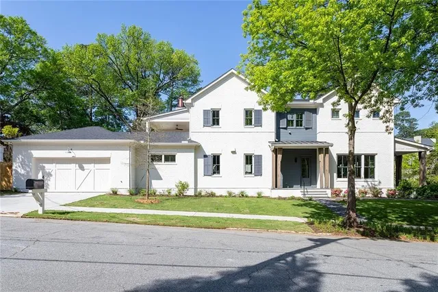 a front view of a house with a garden and trees