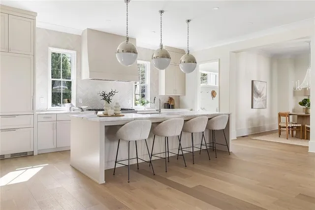 a dining hall with stainless steel appliances kitchen island granite countertop a table chairs and a large window