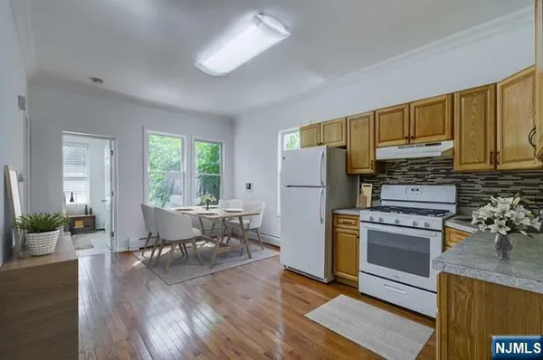 a kitchen with a refrigerator a stove top oven a sink dishwasher and white cabinets with wooden floor