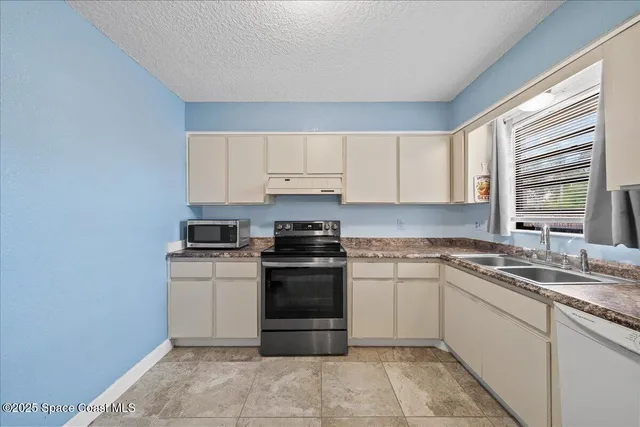 a white kitchen with a refrigerator a sink and a stove