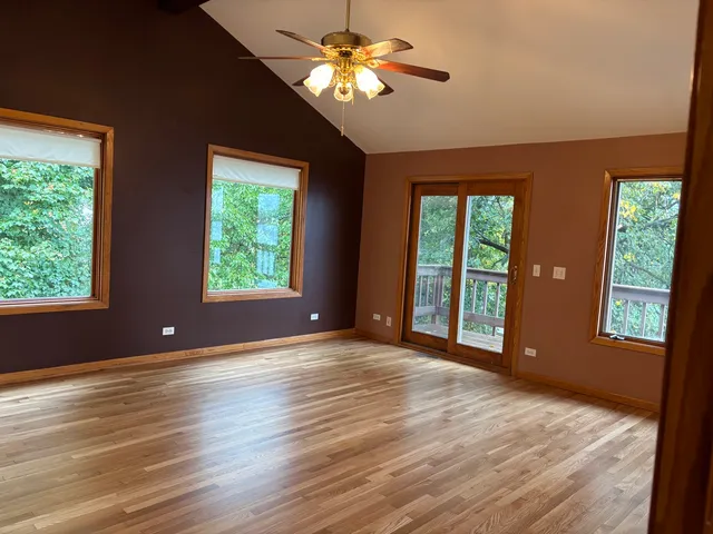 a view of an empty room with window chandelier and wooden floor
