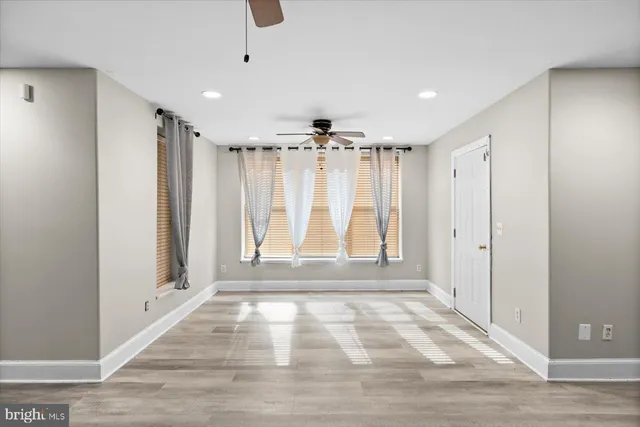 a view of empty room with wooden floor and fan