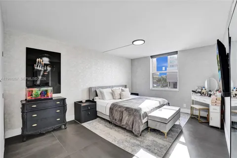 a bedroom with a bed and a flat tv screen on dresser