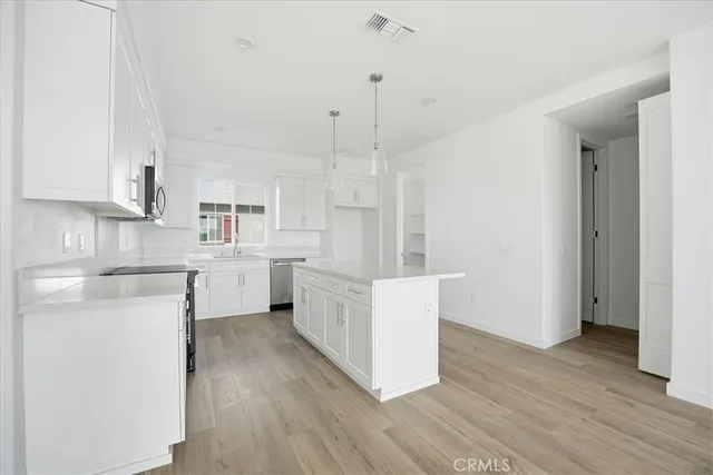 a large kitchen with a wooden floor and white stainless steel appliances