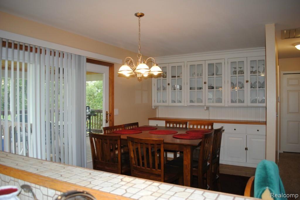 8707 West Van Buren Road Fowlerville, MI 48836 - Photo 6 of 22 Dining room with doorwall to deck and built-in cabinets and counter.