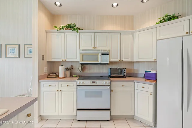 a kitchen with white cabinets and white appliances