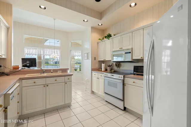 a kitchen with white cabinets appliances and a sink