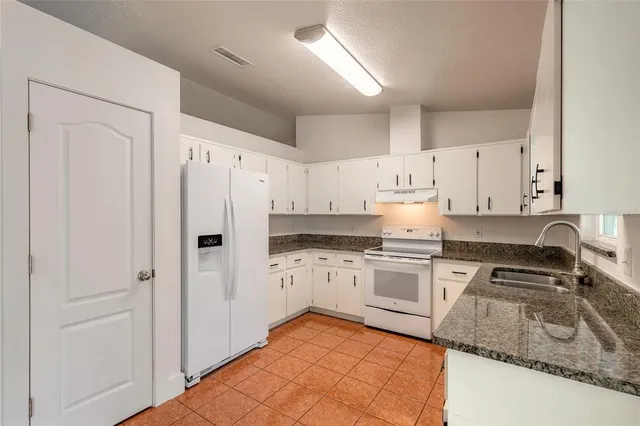 a kitchen with granite countertop a sink and white cabinets