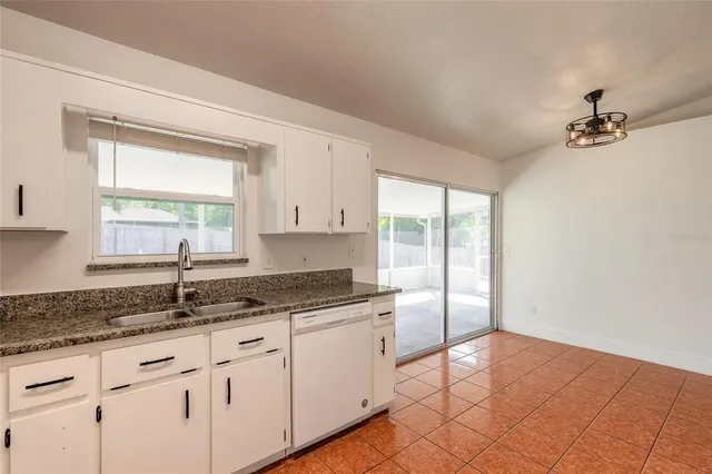 a view of an empty room with window and chandelier fan