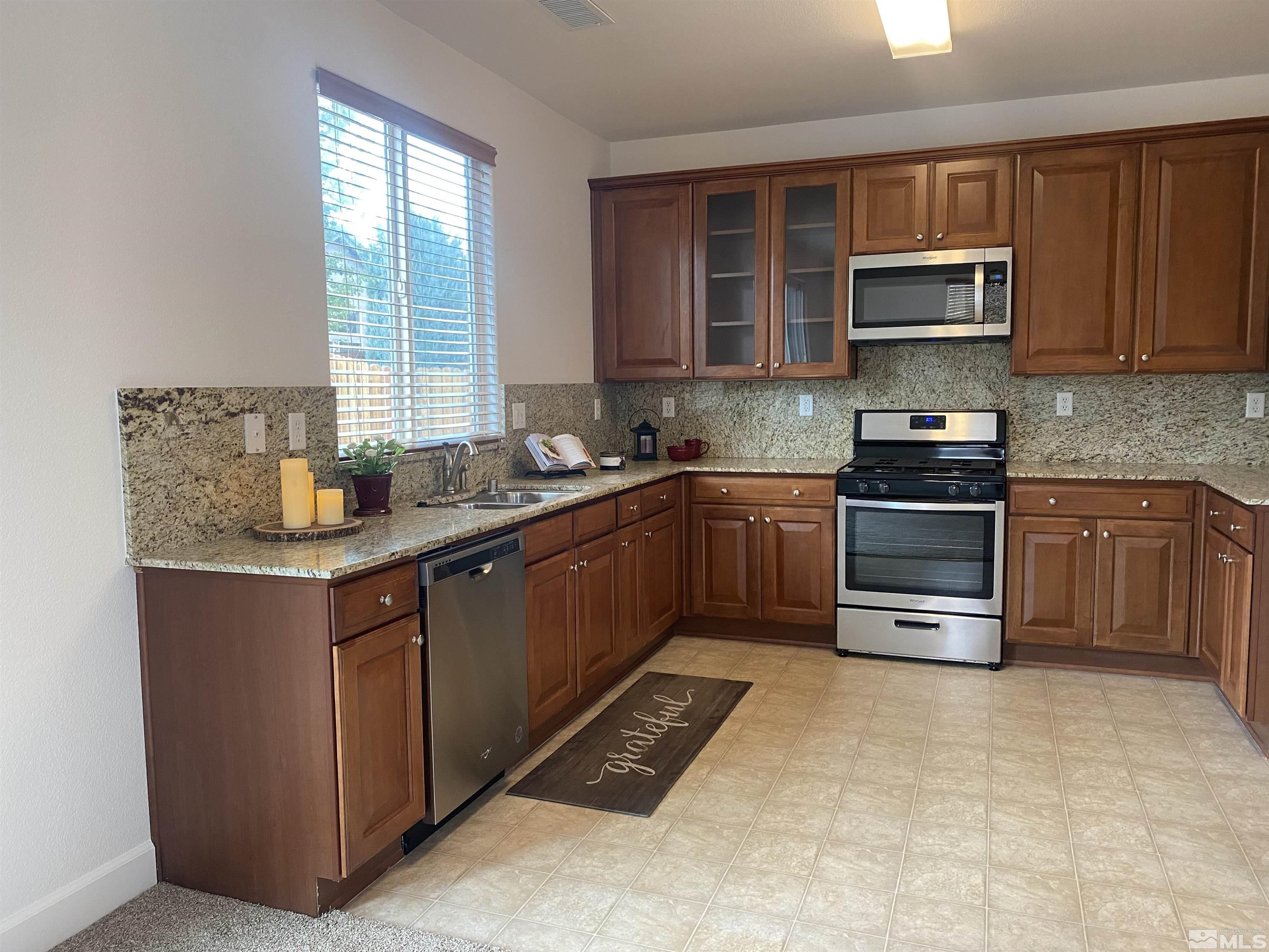490 Pesaro Way Reno, NV 89521 - Photo 11 of 28 a kitchen with stainless steel appliances granite countertop a stove a sink dishwasher and a microwave oven with cabinets