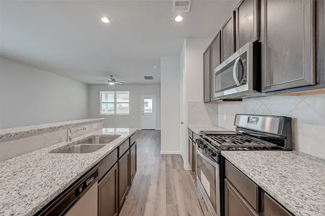 a kitchen with granite countertop stainless steel appliances window a sink and a counter space