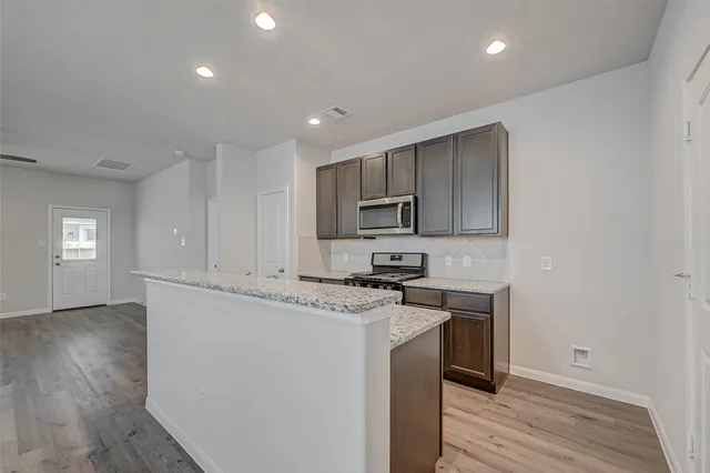 a kitchen with stainless steel appliances granite countertop a stove a sink and a microwave