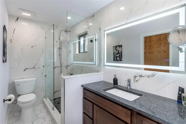 a bathroom with a granite countertop sink toilet and shower
