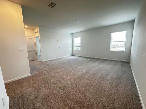 an empty room with windows and refrigerator