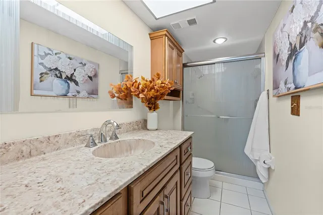 a bathroom with a granite countertop sink a toilet a mirror a vanity and shower