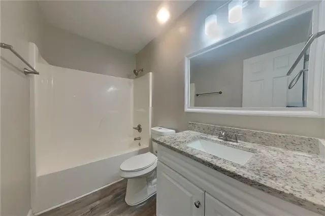 a bathroom with a granite countertop sink a toilet and shower