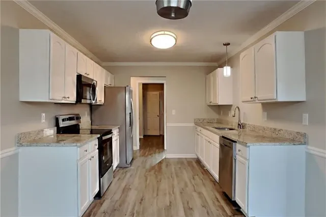 a kitchen with stainless steel appliances granite countertop a stove top oven a sink dishwasher and white cabinets with wooden floor