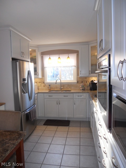 Beautifully updated custom gourmet kitchen with tile floor, quality cabinets, quartz countertops, tile backsplash, and high end stainless steel appliances.