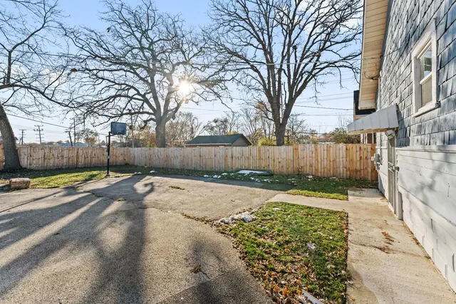 a view of a backyard with large trees and wooden fence