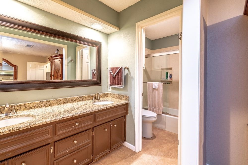 5402 94th Street Lubbock, TX 79424 - Photo 12 of 24 a bathroom with a granite countertop sink and a mirror