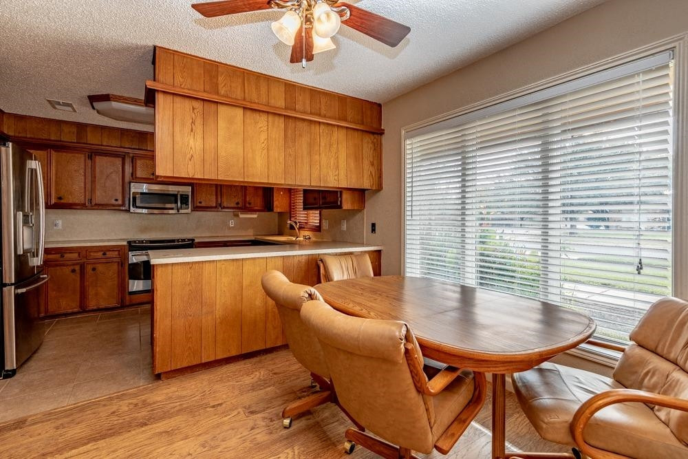 5402 94th Street Lubbock, TX 79424 - Photo 6 of 24 a kitchen with stainless steel appliances granite countertop a sink a stove a kitchen island with chairs and wooden floor