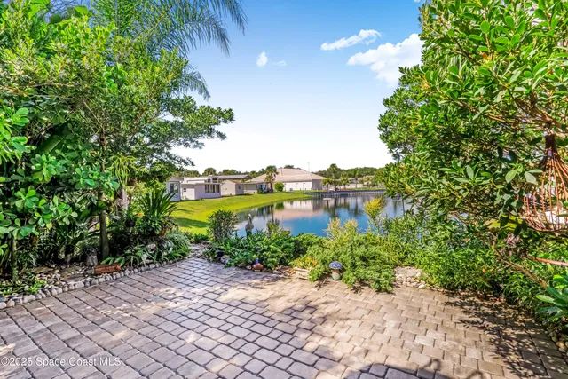 a view of a lake with lawn chairs and large trees