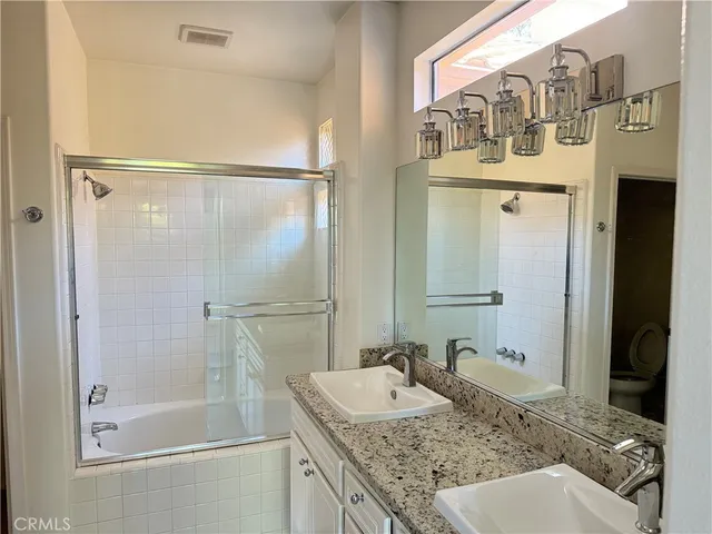 a bathroom with a granite countertop sink mirror and a shower