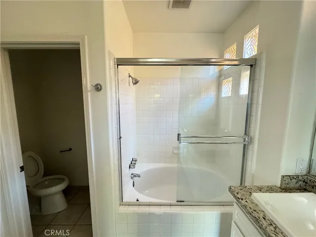 a bathroom with a granite countertop bathtub shower sink and toilet
