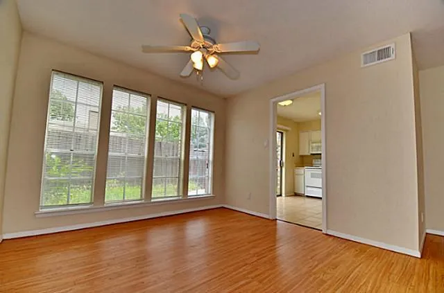 a view of an empty room with wooden floor and a window