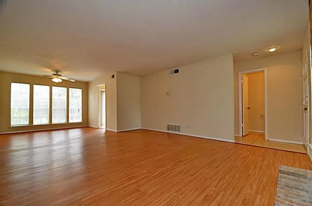 a view of an empty room with wooden floor and a window