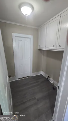 a view of an empty room with wooden floor and cabinets