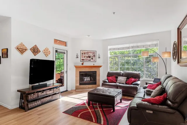 a living room with stainless steel appliances furniture a rug and a window