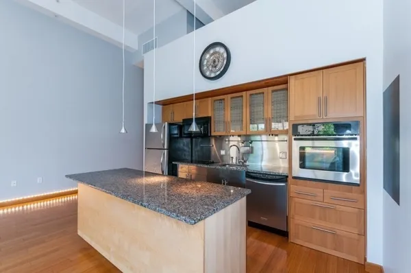 a kitchen with stainless steel appliances granite countertop a granite counter tops and a view of living room