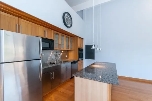 a kitchen with stainless steel appliances granite countertop a refrigerator a stove and a sink